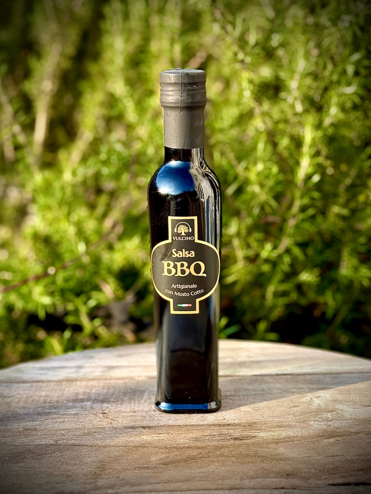 Bottle of Salsa BBQ sauce on a wooden surface with a green outdoor background
