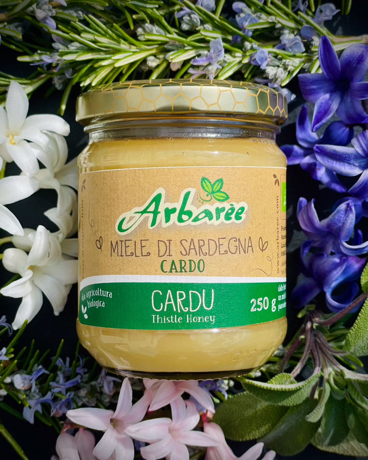 Jar of Sardinian thistle honey surrounded by flowers