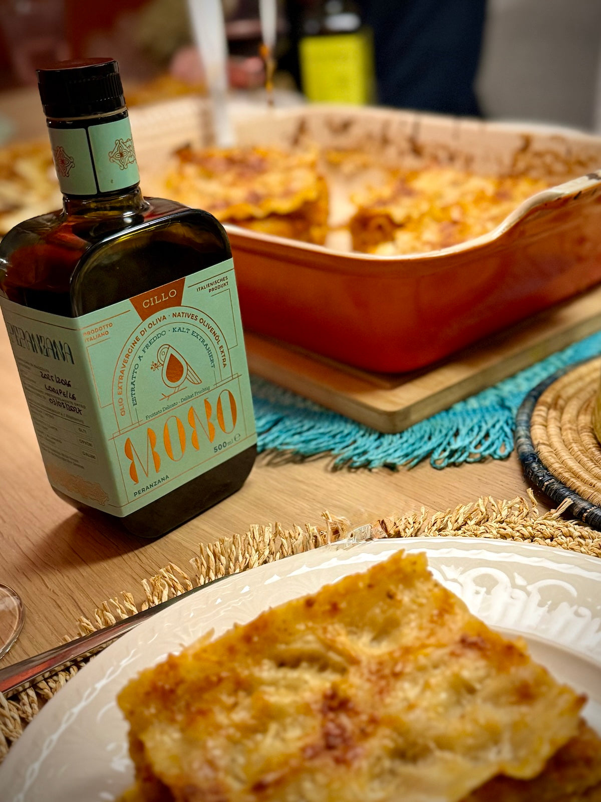 Bottle of Peranzana olive oil with a dish of lasagna in the background