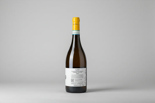 Wine bottle Le Tese from Romanelli with yellow cap on a wooden surface with a blurred green background
