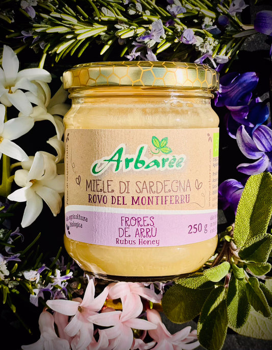 Glas Arbaree-Brombeerhonig, umgeben von Blumen und Grünpflanzen