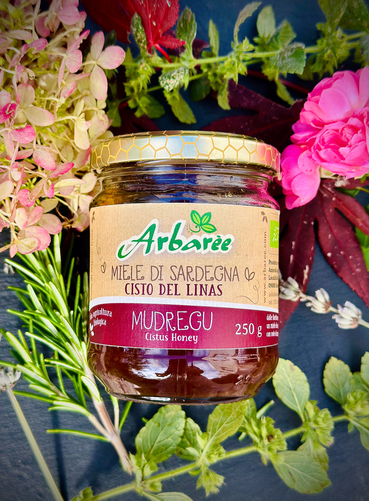 Glas Arbarée-Zistrosenhonig, umgeben von Blumen und Grünpflanzen