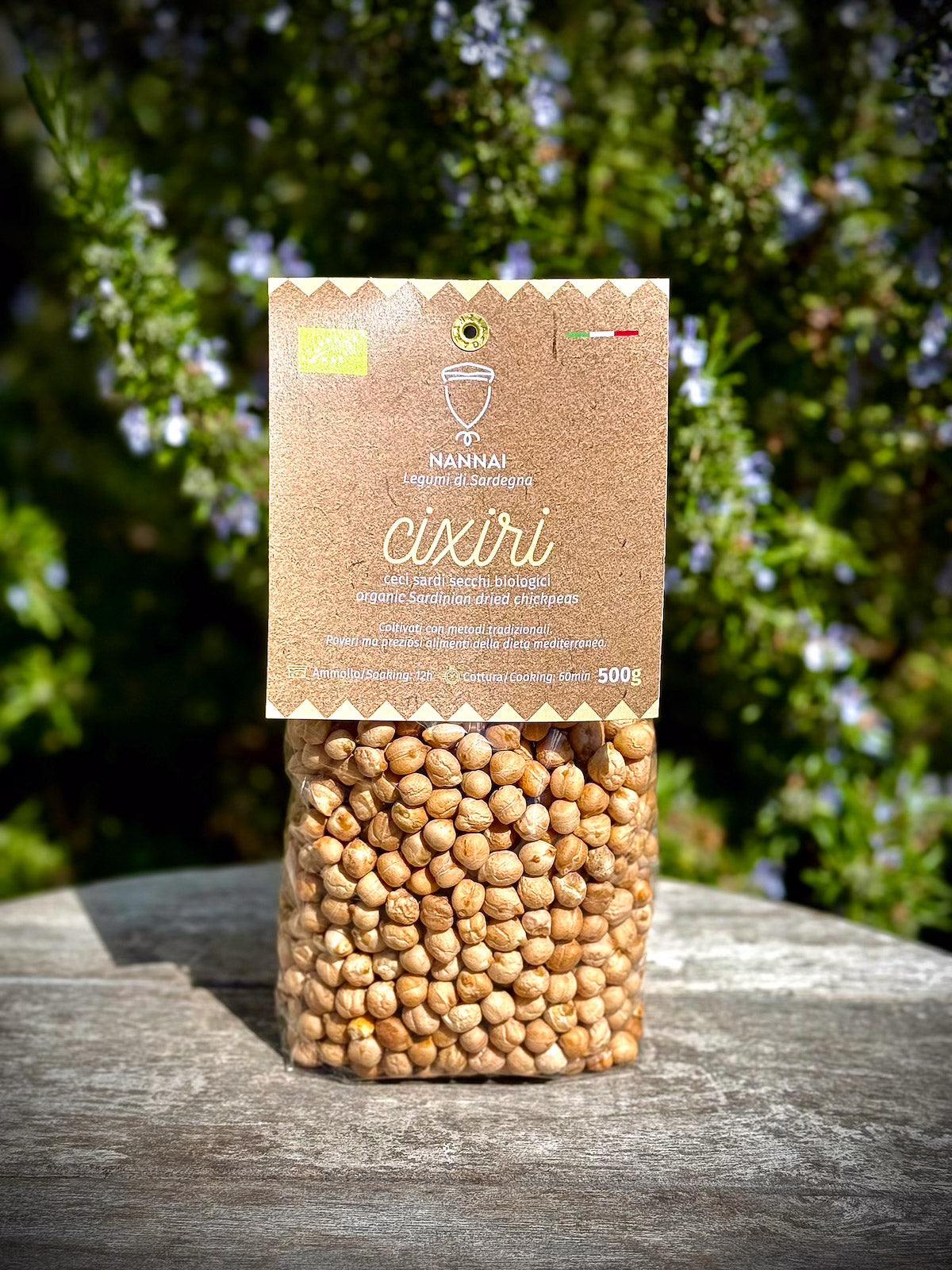 Bag of chickpeas with a brown label on a wooden surface with greenery in the background