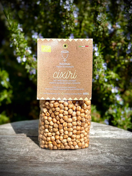 Bag of chickpeas with a brown label on a wooden surface with greenery in the background