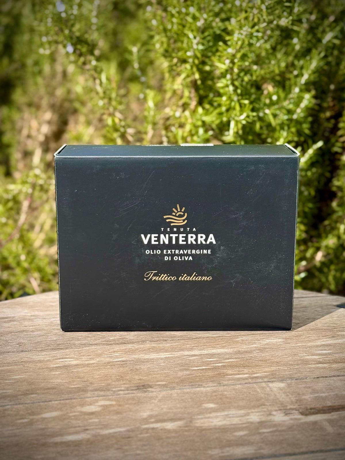 Black box of olive oils with Ventera branding on a wooden surface with greenery in the background