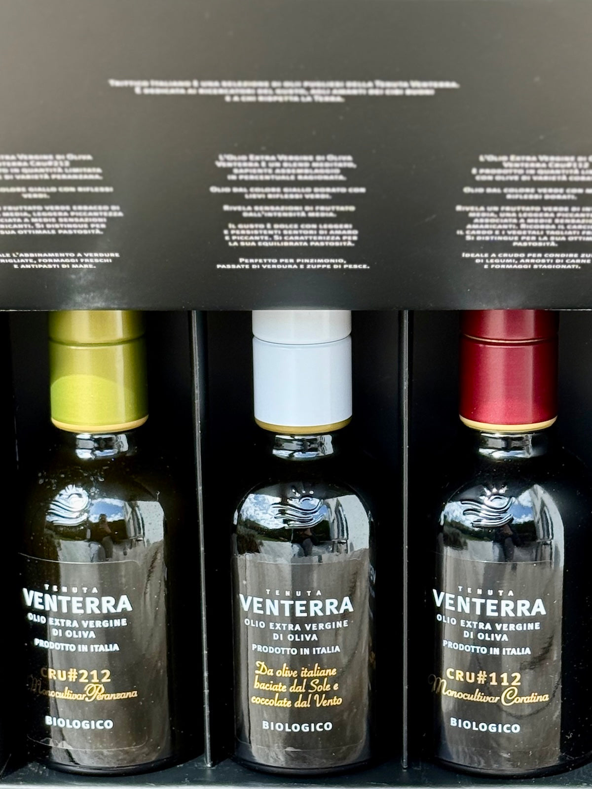 Three bottles of Ventrerra olive oil with black packaging displaying text.