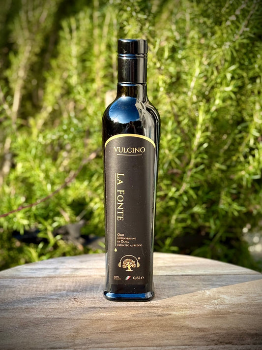 Vulcino La Fonte olive oil bottle on a wooden surface with a natural background