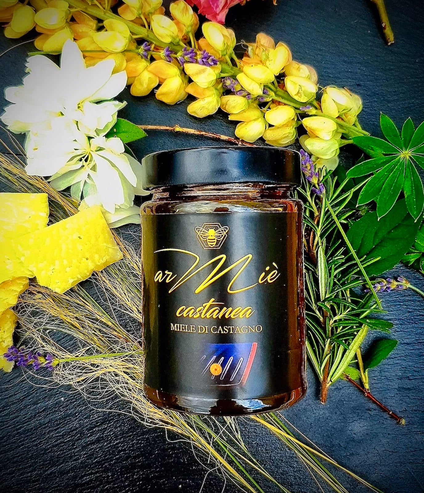 Glas Kastanienhonig mit Blumen- und Grünarrangement auf dunkler Oberfläche