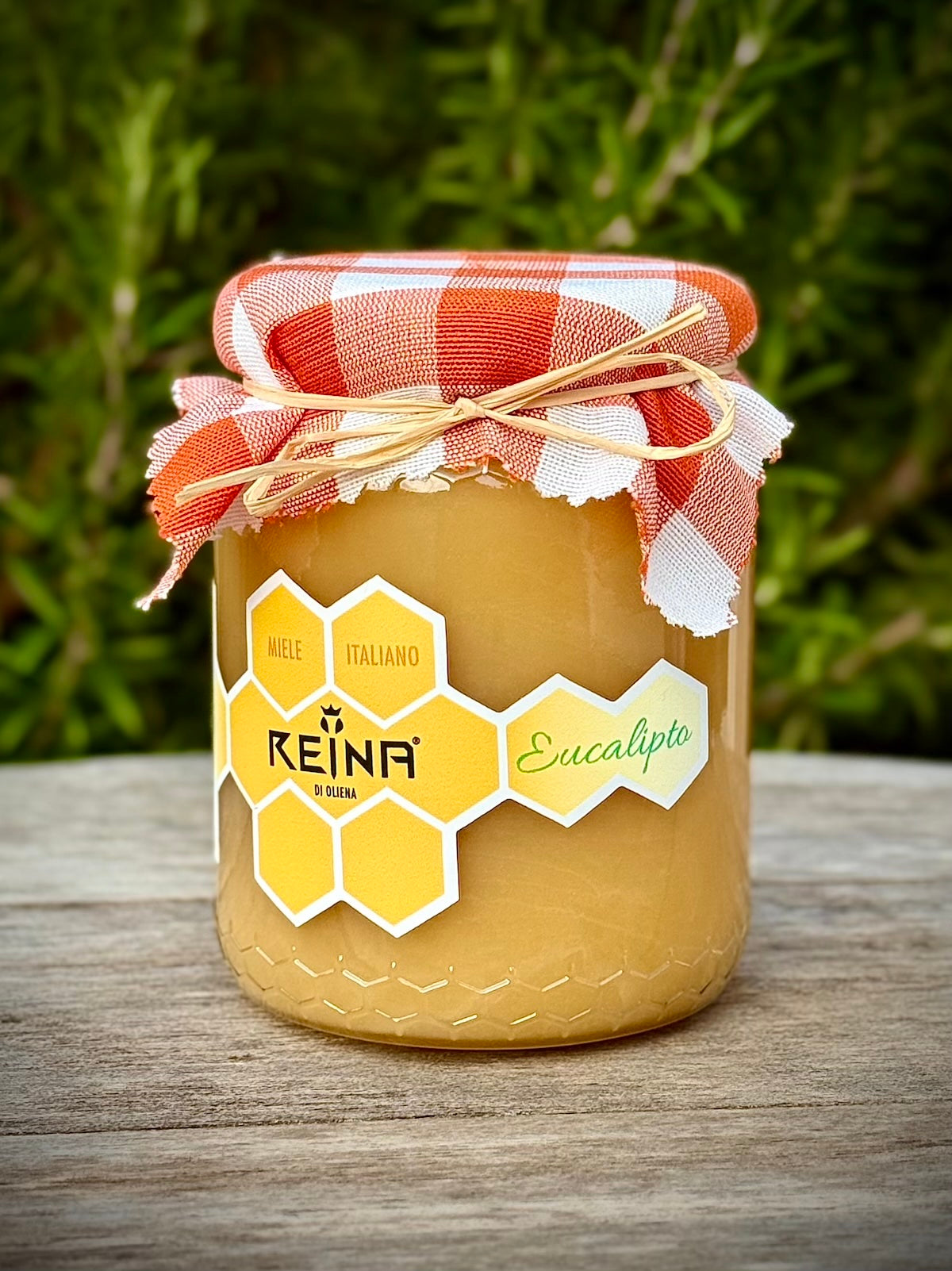 Jar of eucalyptus honey with a Reina label on a wooden surface with a natural background
