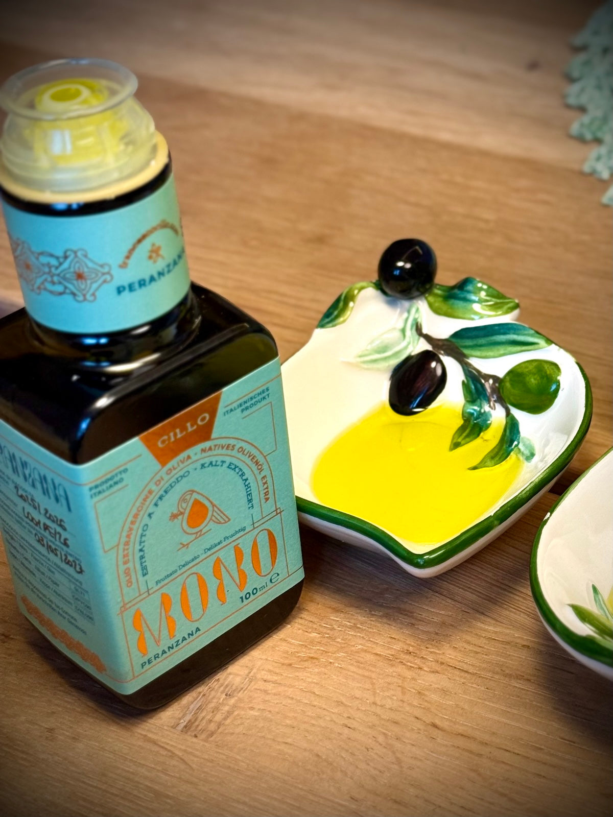 Bottle of Peranzana olive oil with a decorative lid on a wooden surface