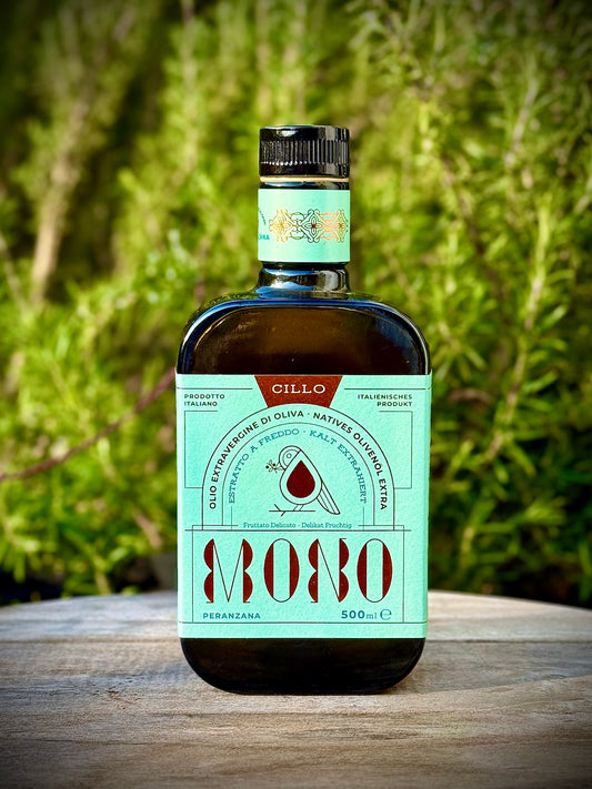 Bottle of Peranzana  Mono olive oil with a green label on a wooden surface with a blurred natural background