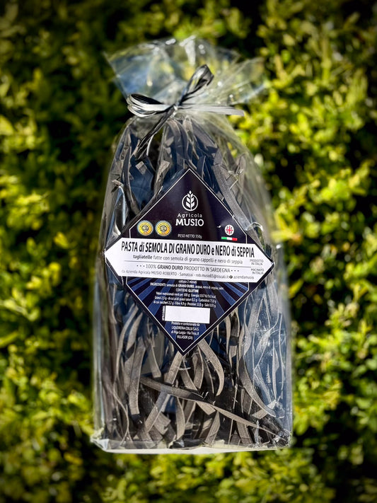 Pack of tagliatelle with cuttle fish ink on a green background