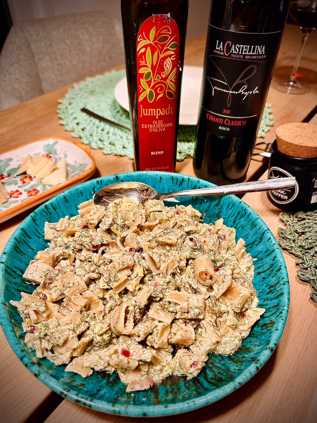 Pasta calamarata in a blue bowl with a wine bottle in the background.