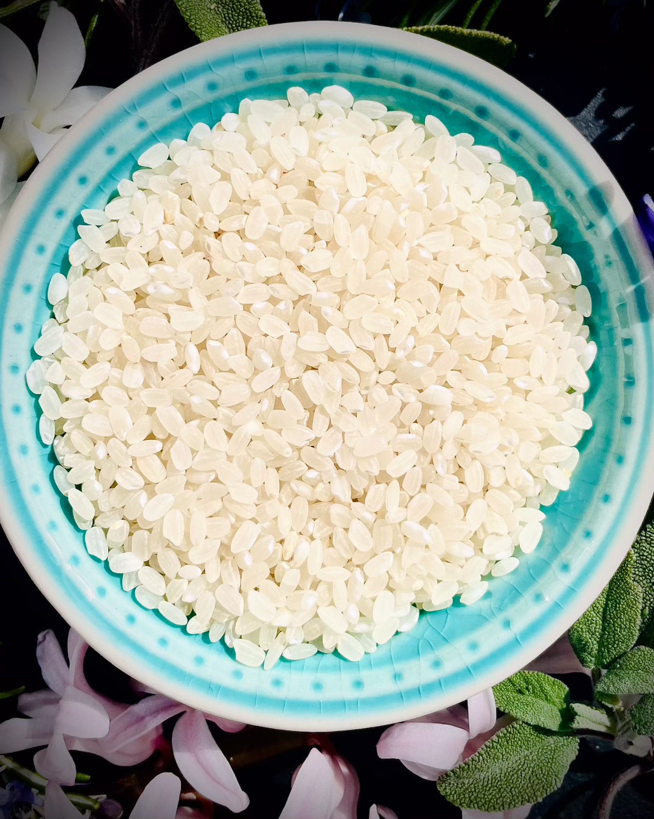 White rice in a blue bowl with flowers and leaves in the background