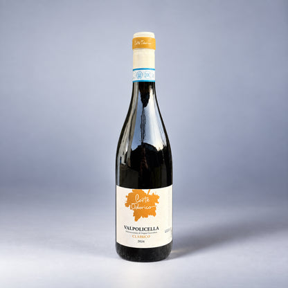 Eine einzelne Flasche Valpolicella Classico der Marke Corte Odorico vor einem neutralen grauen Studiohintergrund.