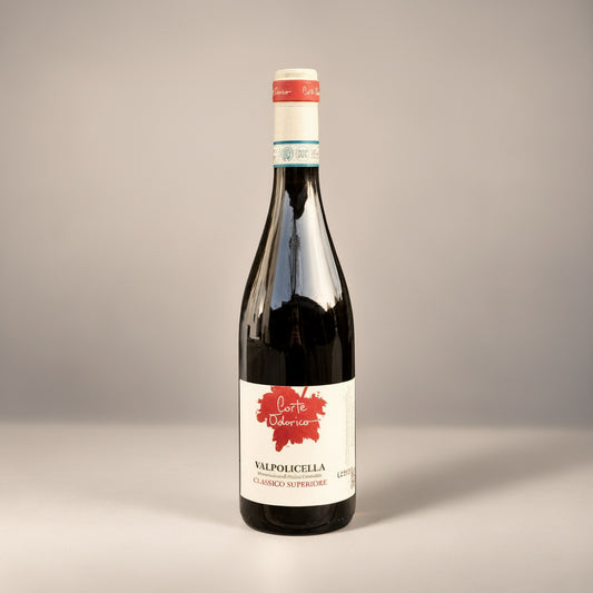 Eine einzelne Flasche Valpolicella Classico Superiore der Marke Corte Odorico vor einem neutralen grauen Studiohintergrund.