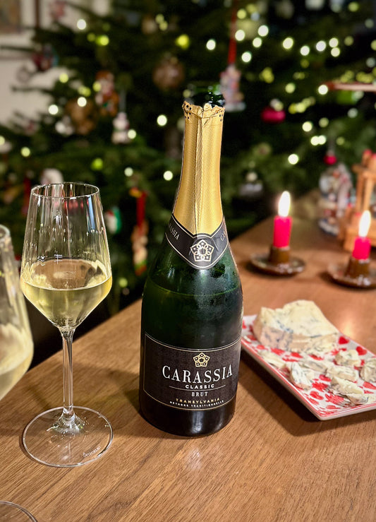 Bottle of Carassia wine with a glass on a table in front of a decorated Christmas tree.