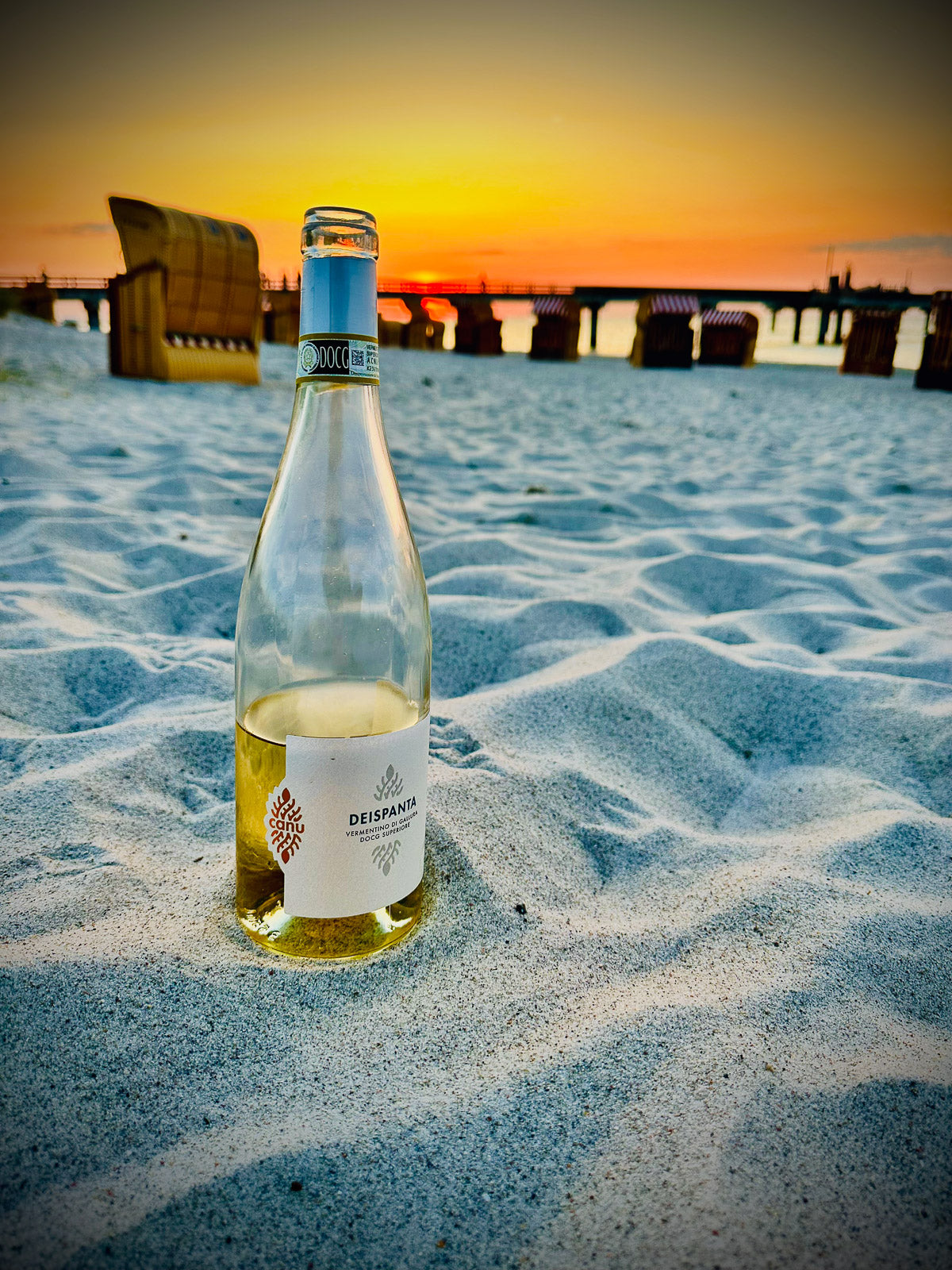 Eine Flasche Deispanta Vermentino auf Sand