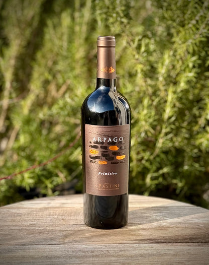 Wine bottle labeled 'Arpago' on a wooden surface with a blurred green background