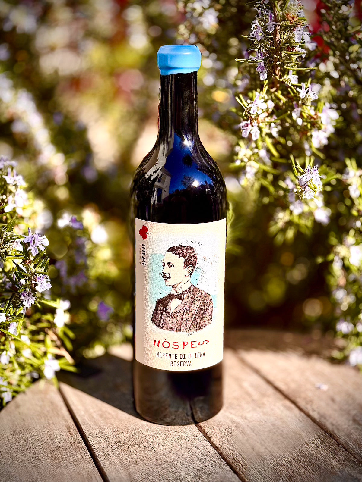 Wine bottle with a label featuring a portrait on a wooden surface with flowers in the background