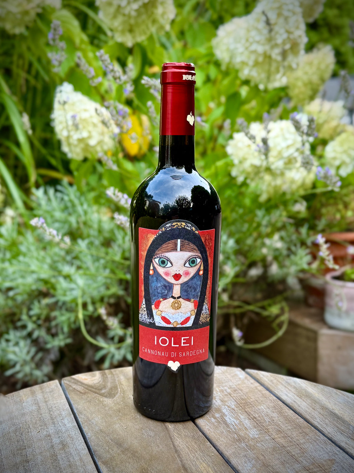 Bottle of Iolei wine on a wooden table with flowers in the background