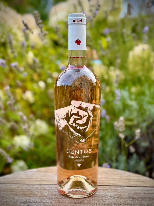 Bottle of Juntos wine on a wooden surface with a blurred natural background