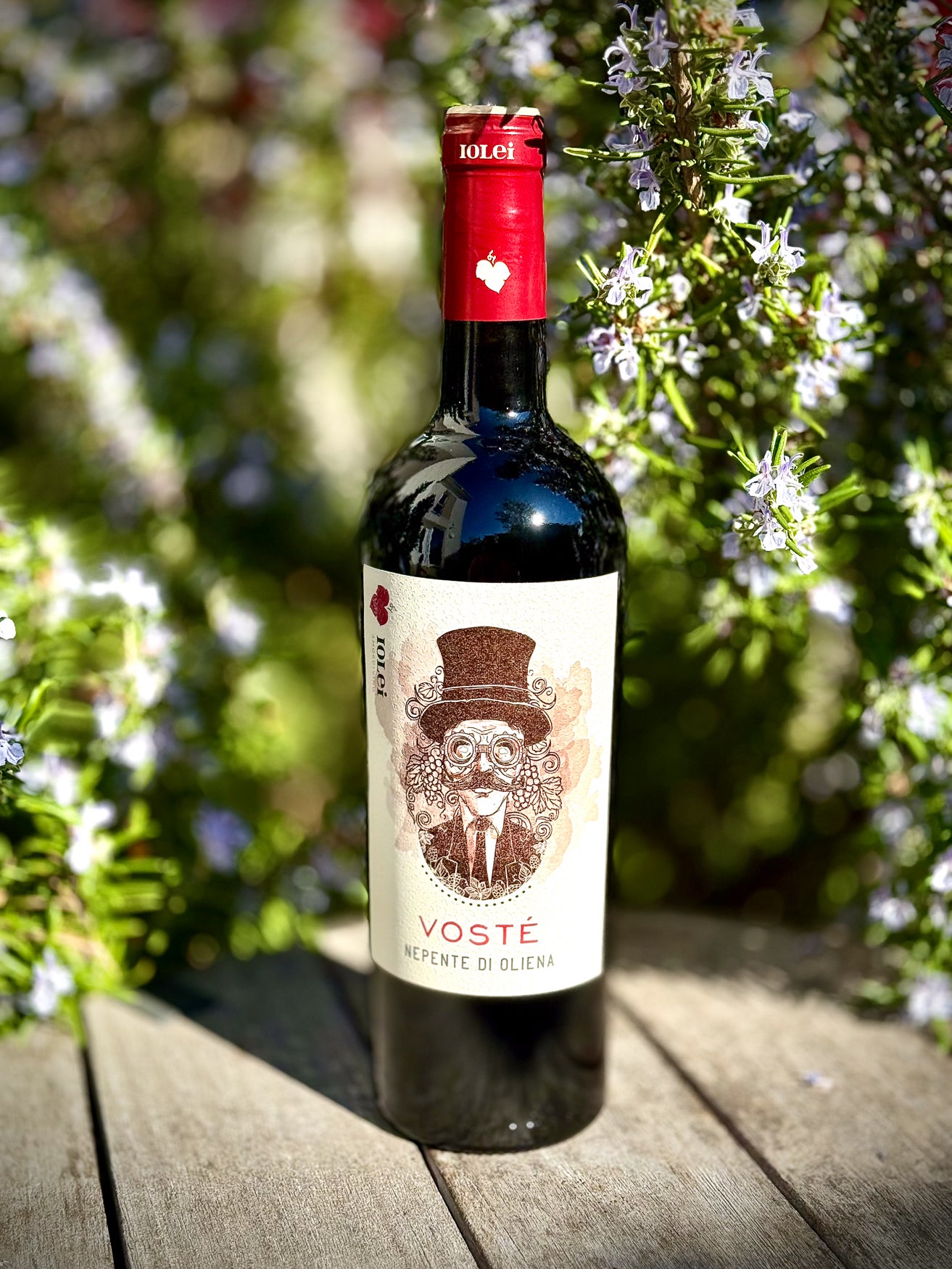 Bottle of Voste Cannonau on a wooden table with rosemary in the background
