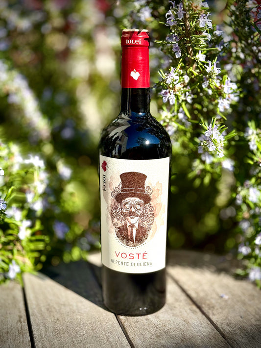 Bottle of Voste Cannonau on a wooden table with rosemary in the background