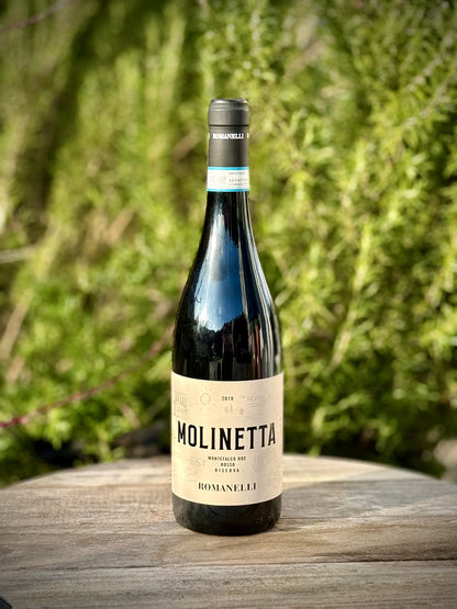 Eine Flasche Molinetta von Romanelli vor einem grünen Gartenhintergrund.
