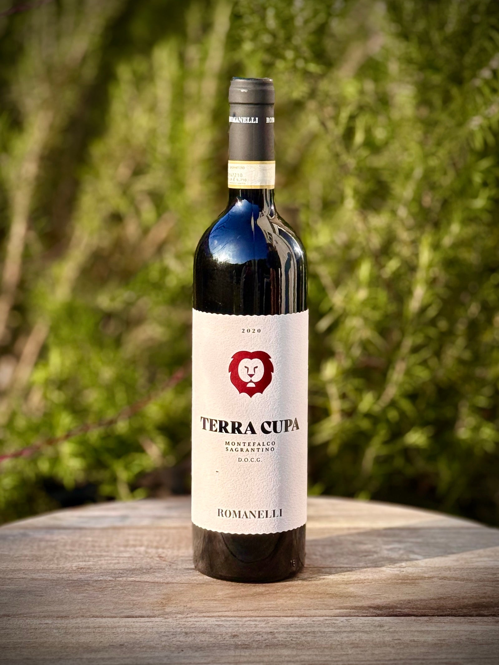 Bottle of Terra Cupa wine on a wooden surface with a blurred green background