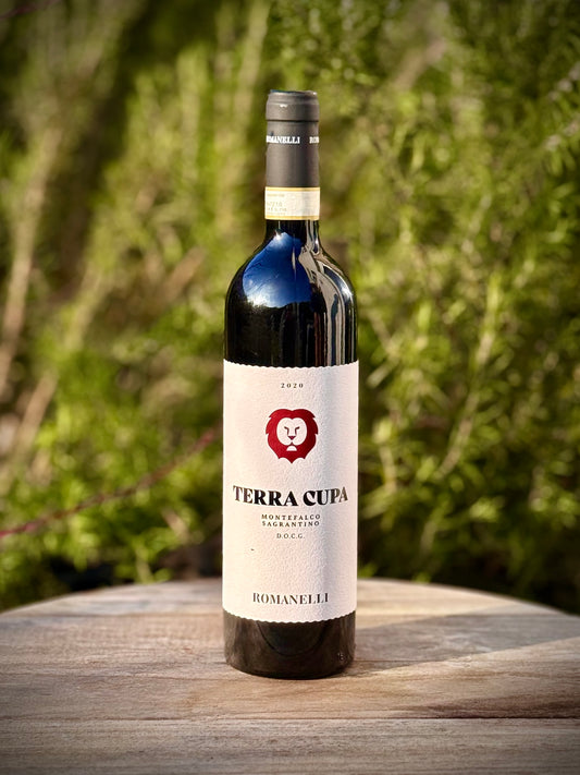 Bottle of Terra Cupa wine on a wooden surface with a blurred green background