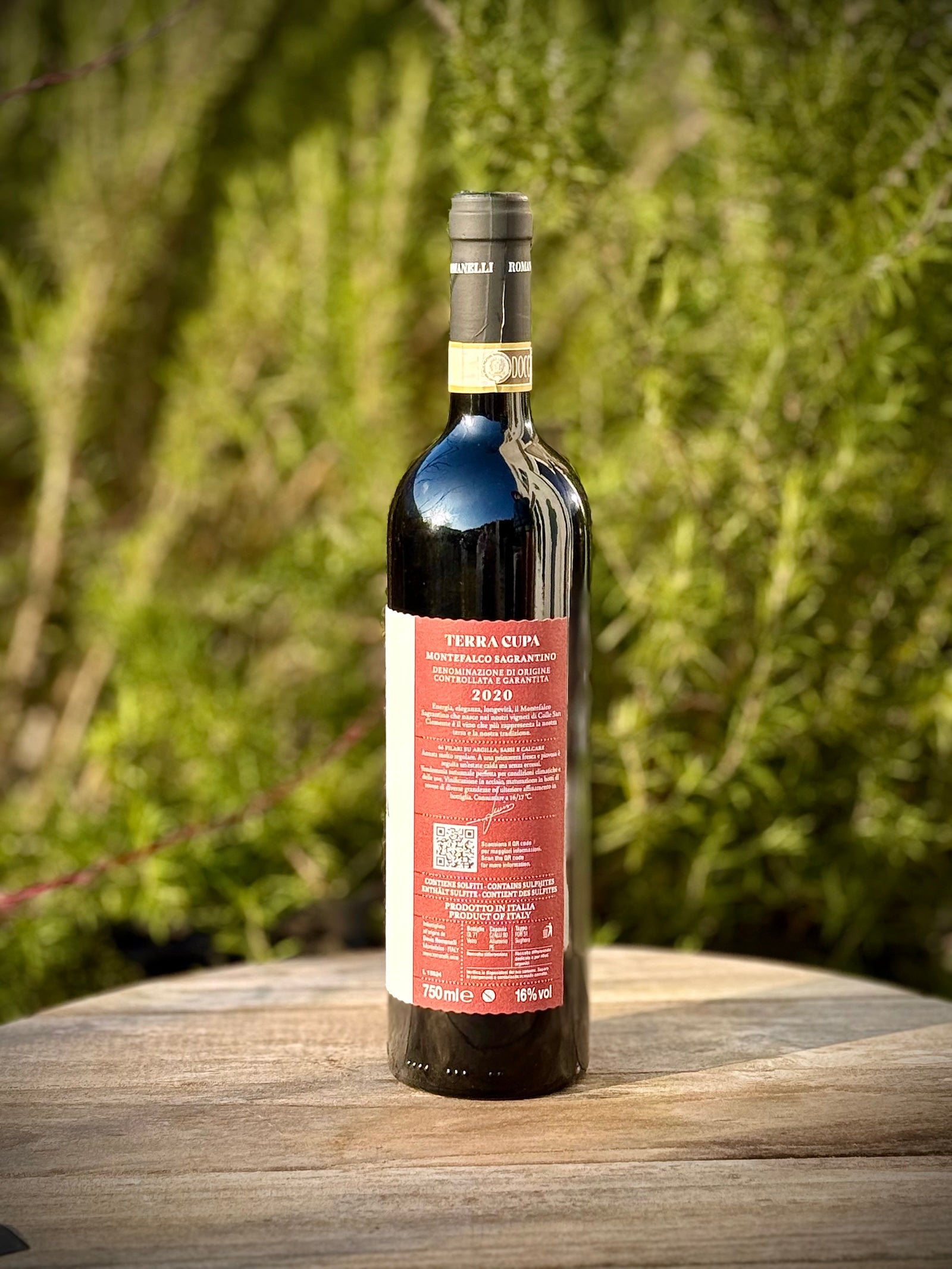 Bottle of Terra Cupa red wine on a wooden surface with a blurred green background