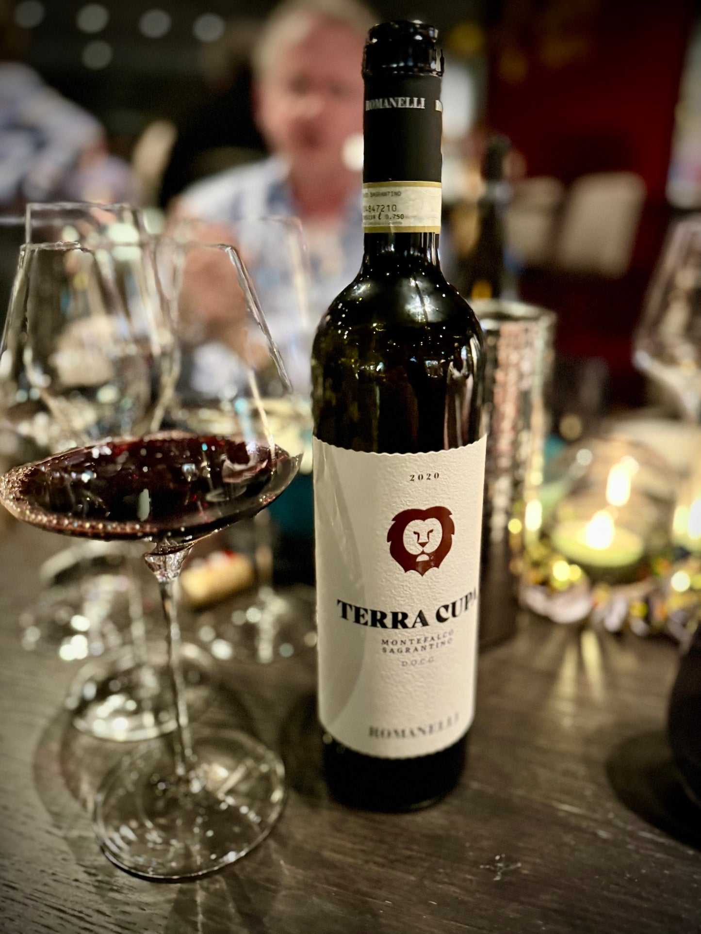 Bottle of Terra Cupa wine on a table with glasses in a blurred restaurant setting