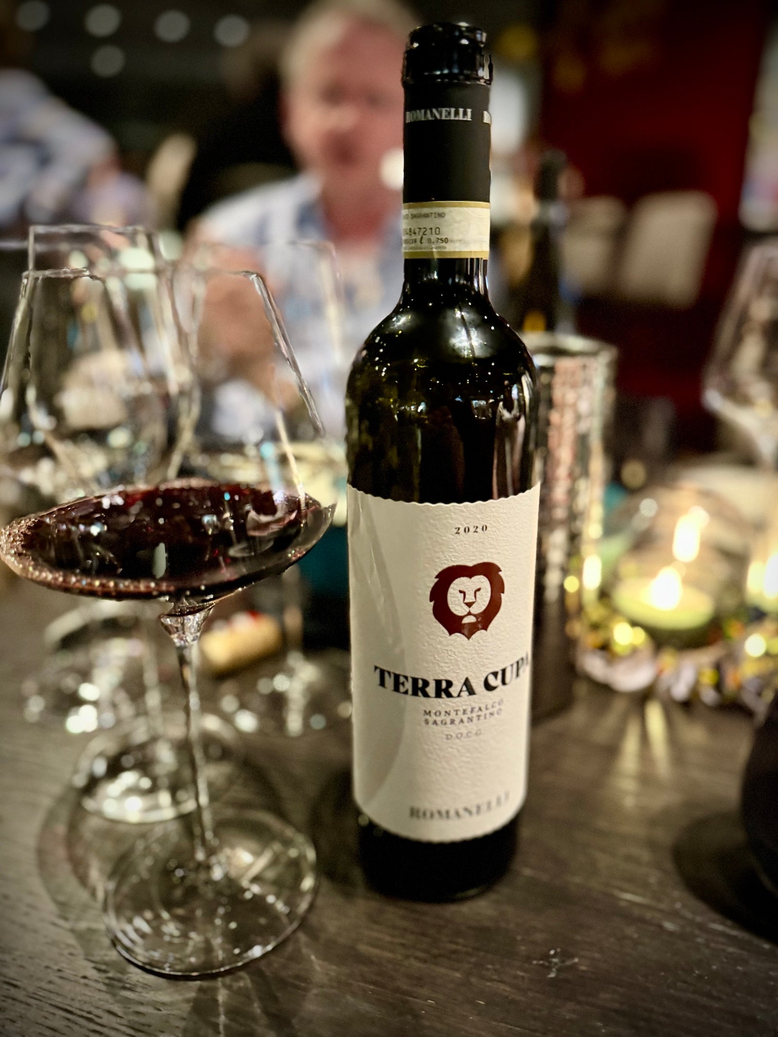 Bottle of Terra Cupa wine on a table with glasses in a blurred restaurant setting