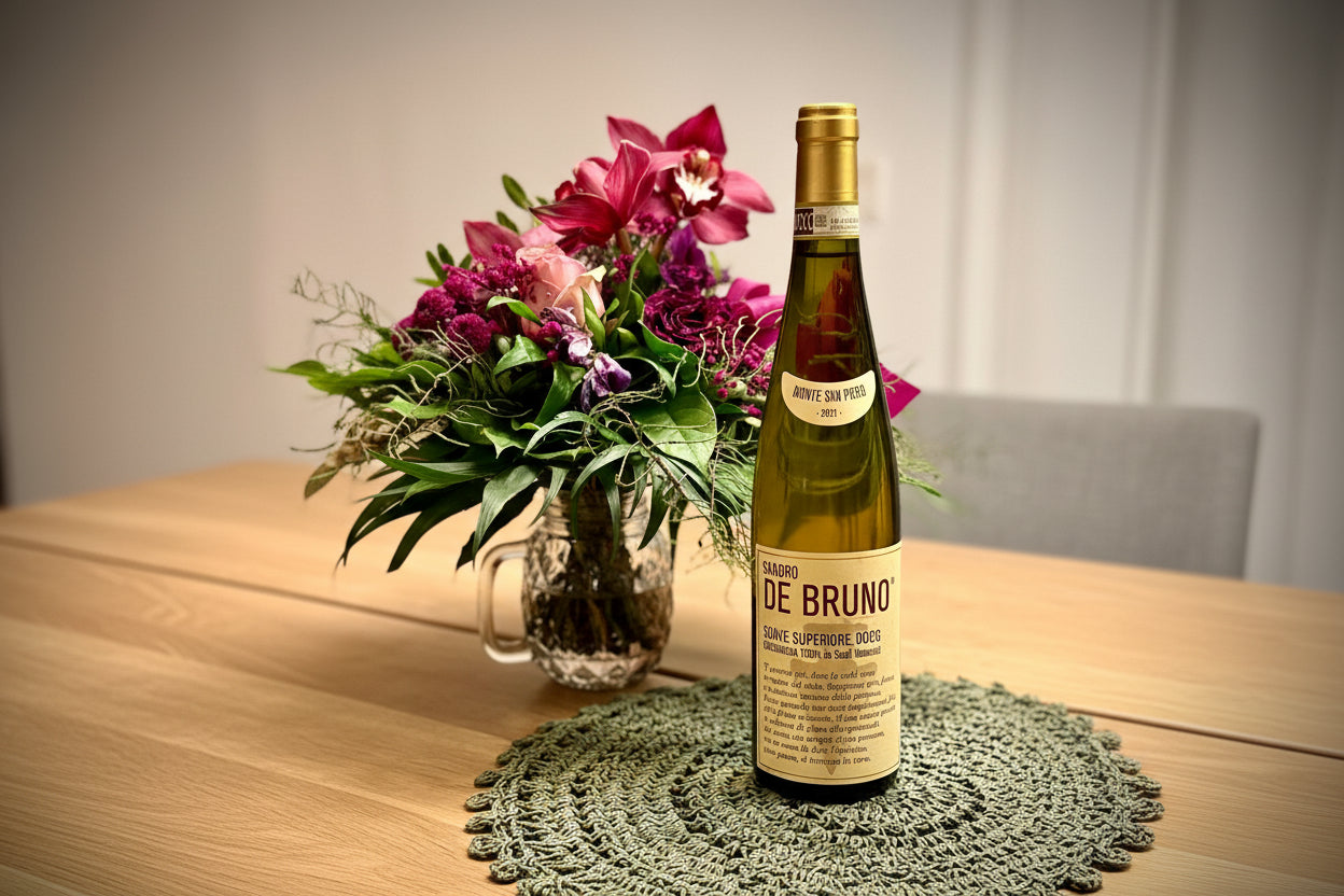 Bottle of Sandro de Bruno Soave wine with a bouquet of flowers on a table.